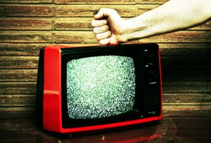 An angry fist smashing down on a broken TV.